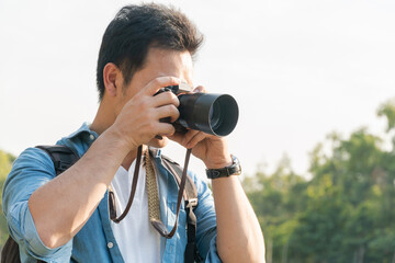 Asian man photographer shooting landscape picture with camera outdoor at park, travel, career freelancer or leisure activity concept, with copy space