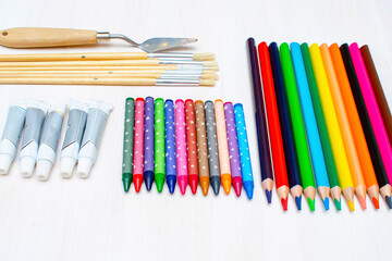 Paintbrushes, palette knife, colorful pencils, pastel crayons. Creativity creation workplace process. Artist's stuff on white table.Top view Flatlay of drawing supplies