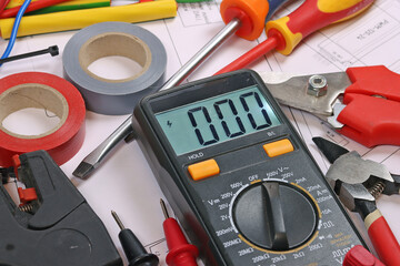 Multimeter and tools for electrical installation in a close-up schematic diagram.