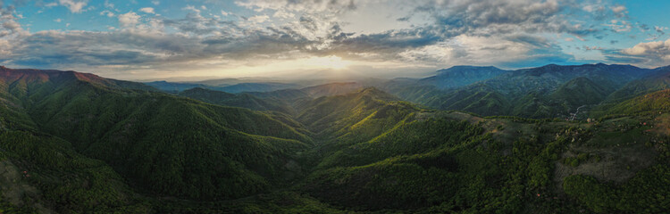 High angle aerial view drone image of sunset sun rays trough the trees and forest in mountain range...