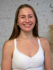 Beautiful athletic woman with long hair in a white T-shirt. Portrait, close-up, light interior.