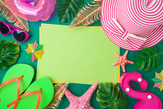 Frame border design for summer vacation concept Beach accessories and tropical leaves with paper note on green background. Top view, flat lay