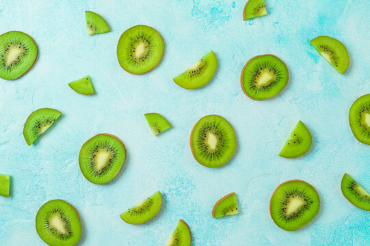Colorful fresh kiwi fruit slices on blue background. Summer healthy food concept. Top view, flat lay