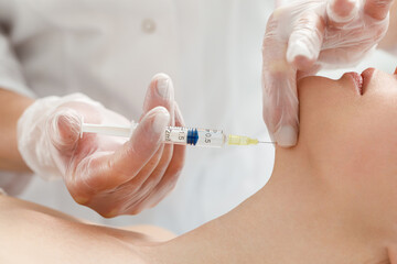 Cosmetologist performs the chin lift procedure by injecting beauty injections. Doctor injecting...
