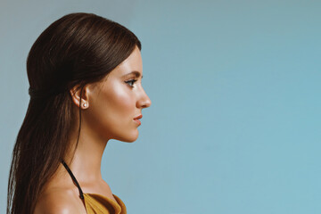 Young girl with smooth shiny skin in profile on a blue background, close-up