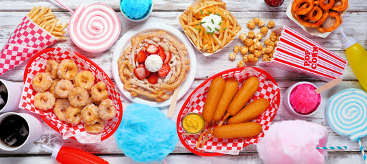 Carnival theme food table scene over a white wood banner background. Top view. Summer fair concept....