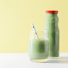 healthy green smoothie in glass, bottle with straw on yellow background. Vegetarian healthy lifestyle concept.refreshing drink. quick snack. square