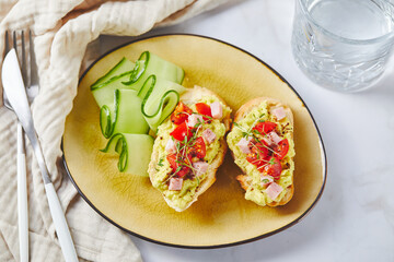 Crostini or bruschetta with softened avocado, ham and tomatoes. Toast with mashed avocado