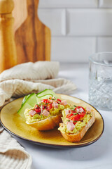 Crostini or bruschetta with softened avocado, ham and tomatoes. Toast with mashed avocado