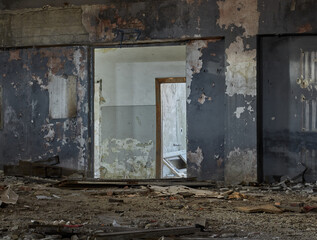 Abandoned ruined interior of building.  Door without a door. Old destroyed walls with garbage and dirt. 
