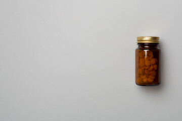 Glass bottle with pills on color background, top view