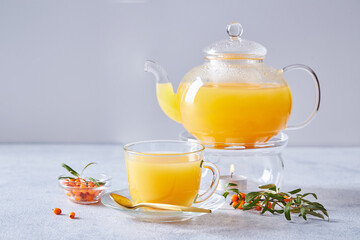 Glass teapot with sea buckthorn tea on a light background