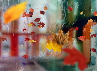 Autumn leaves and rain drops on window view on street  urban scene Weather forecast 