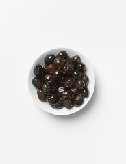black olives in a white bowl, on a light background, view from above