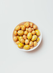 large green olives in a white bowl, on a light background, view from above