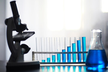 Test tube with blue liquid on the laboratory table. Examination of liquid under a microscope.