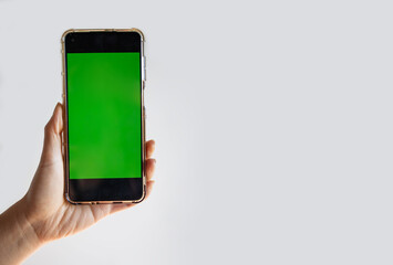 Isolated human left hand holding black mobile smart phone with green screen for video production 