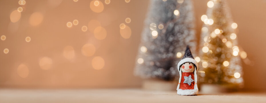 Weihnachten - kleine, niedliche Figur vor Deko Weihnachtsbäumen mit Lichterkette in Silber und Gold auf Holz 