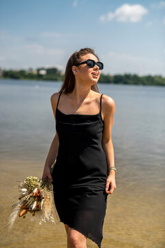 young sexy woman in black dress walking of the lake