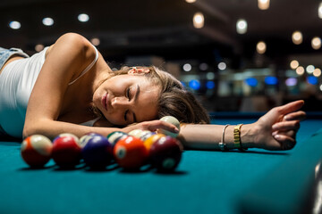 charming woman in a white T-shirt lies on a pool table