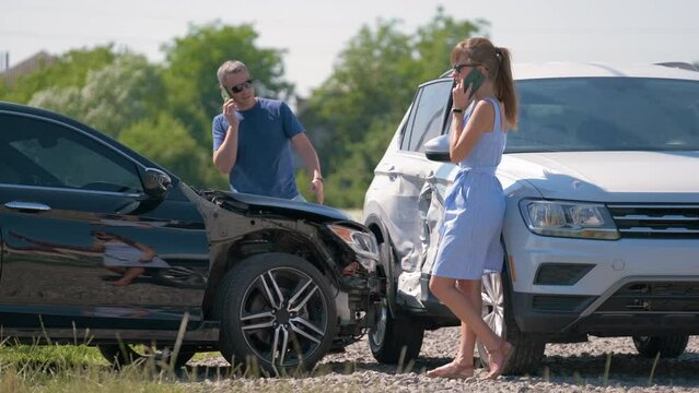 Angry woman and man drivers of heavily damaged vehicles calling insurance service for help in car crash accident on street side. Road safety concept