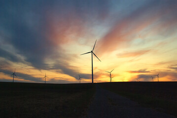Obraz premium wind farm windmills in dramatic light and mystical sunset atmosphere