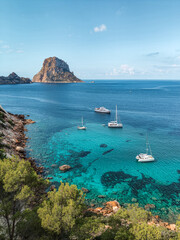 View of Es Vedra island with boats in the sea, Ibiza island, Spain