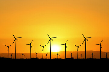 The concept of alternative energy, wind energy and clean energy. Silhouettes of wind turbines generate electricity in a field.