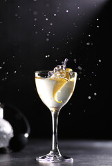 Drinks and cocktails. Light beverage with ice, lemon twist in a large transparent glass on black table, splash. Restaurant, bar. Background image, copy space