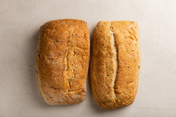 Fresh homemade bread on a gray cement background. Bread with flax seeds, sunflower seeds and sourdough bran. Organic homemade baked goods. Place to copy.