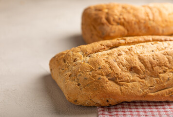 Fresh homemade bread on a kitchen towel on a gray cement background. Bread with flax seeds, sunflower seeds and sourdough bran. Organic homemade baked goods. Place to copy.