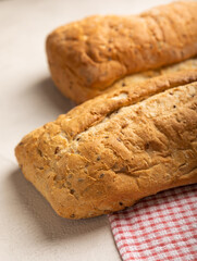 Fresh homemade bread on a kitchen towel on a gray cement background. Bread with flax seeds, sunflower seeds and sourdough bran. Organic homemade baked goods. Place to copy.