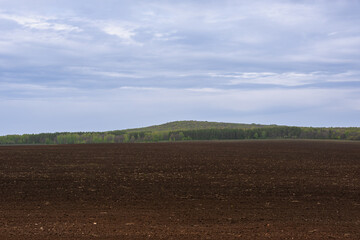 Fototapeta na wymiar Field before planting, hills and forest in the background.