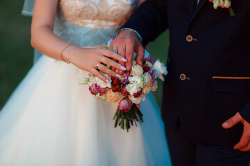 Wedding bouquet in the hands of the bride at the ceremony. The touch of the hands of the newlyweds. Autumn wedding concept. Wedding accessories. Bride manicure.