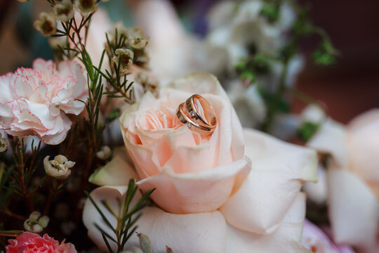 Wedding rings on a wedding bouquet. Floristry for a wedding ceremony. Delicate bouquet of roses in a dark vintage interior.