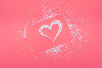 Heart made of powdered sugar on a pink background