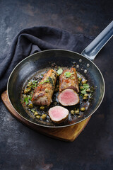 Traditional fried duroc pork fillet pieces with capers and spices served as close-up in a rustic...