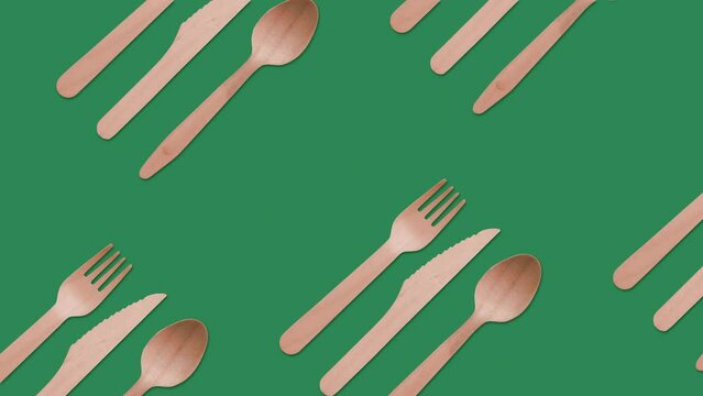 Pattern of eco, disposable takeaway wooden cutlery (fork, knife, spoon) on green background. Plastic free, biodegradable, green screen, looping animation.