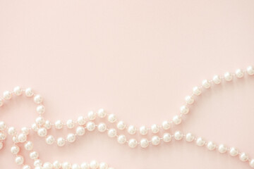 Pearl beads on pastel pink horizintal background with copy space.