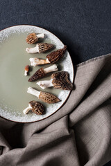 Naklejka premium Morel mushrooms on a plate on black background