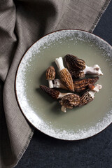 Morel mushrooms on a plate on black background