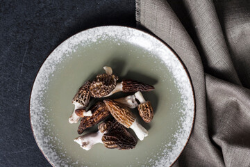 Morel mushrooms on a plate on black background