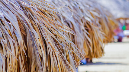 Bamboo beach umbrellas with palm roofs. Sunny day on a VIP beach in Vietnam in summer. 