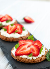 Healthy sandwich with strawberry and cream cheese on slate board. Tasty breakfast. Clean eating, diet or easy recipe of vegetarian sandwich for vegan menu.