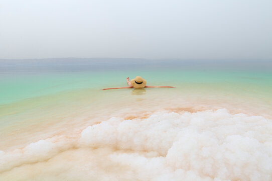 Girl with hat is relaxing and swimming in the Dead Sea