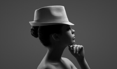 Black-white portrait of a girl in a hat with deep shadows.
