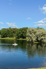 vacationers ride a boat on a forest lake against the backdrop of a park and blue sky