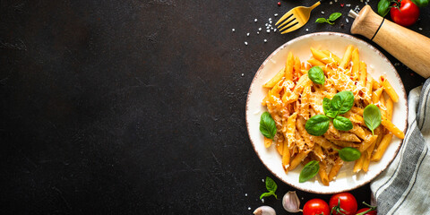 Pasta with tomato sauce, basil and parmesan on dark table. Penne pasta with tomato sauce alla arrabbiata. Long banner format.