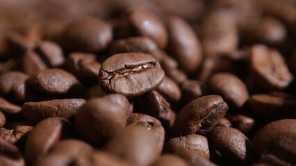 Naklejka premium close-up on a coffee bean that is among other grains in the dark