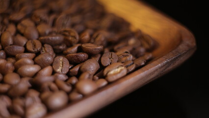 coffee beans are in a wooden plate on a black background